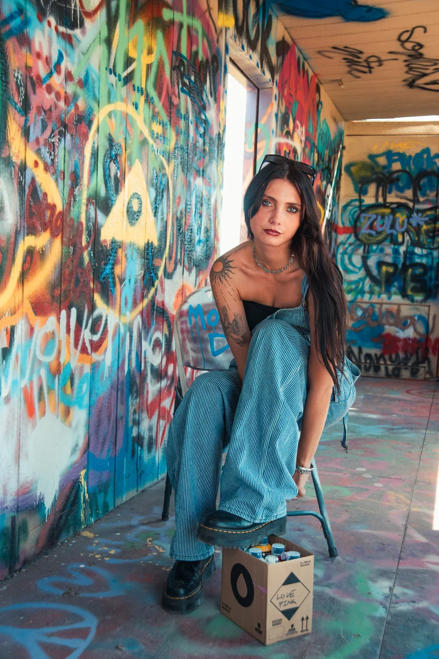 Austin music photographer Faith Addison sitting on a chair in a graffiti-covered room